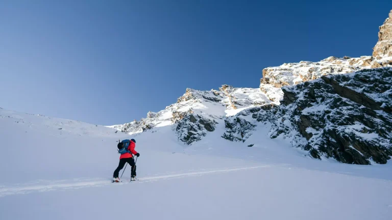 Ein Skifahrer geht den Berg hinauf. Skitournee in den Alpen. Sonniges Wetter. Abenteuer Wintersport